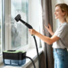 Green portable steam cleaner used on a window Green portable steam cleaner used on a window